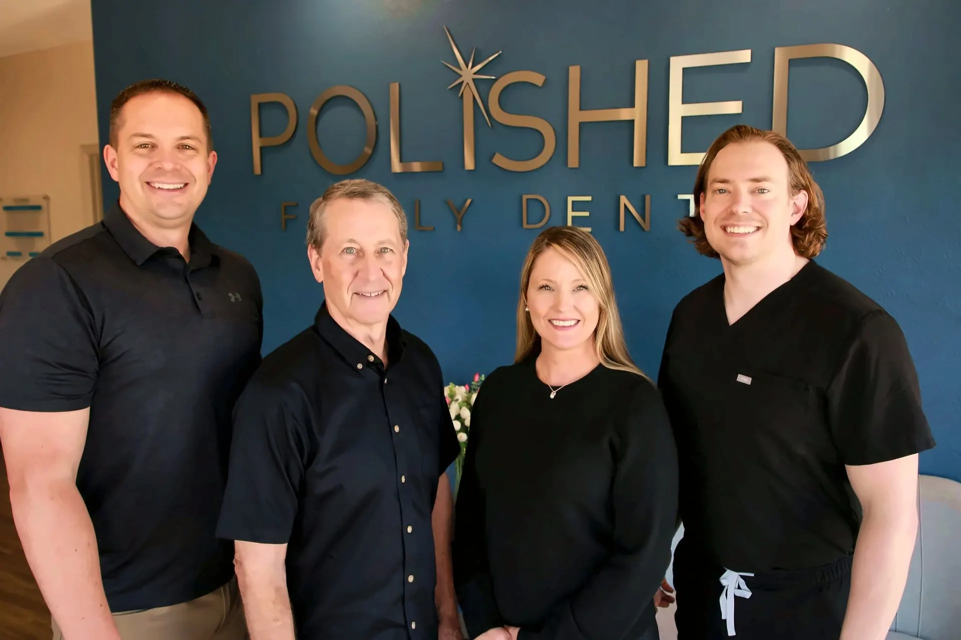 Dentistas de Polished Family Dental frente al letrero del consultorio
