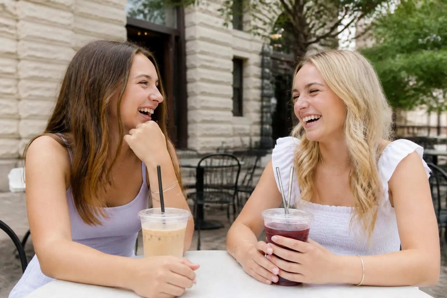 Two teenage friends laughing at a café patio