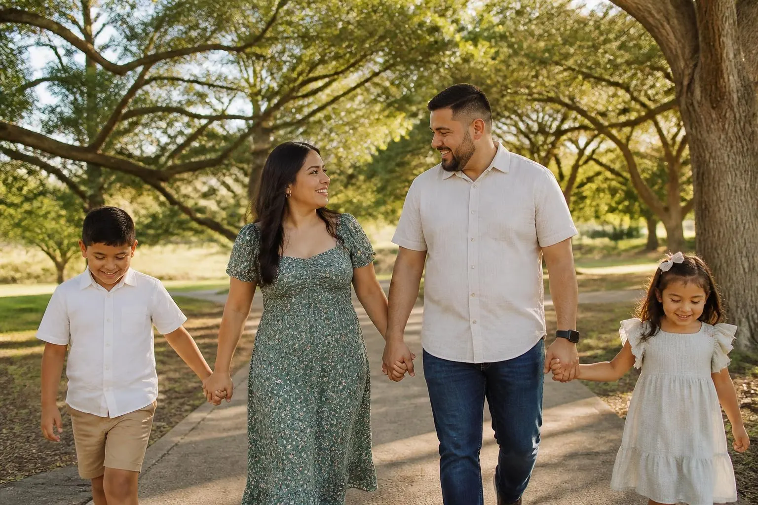 Familia de cuatro caminando por un sendero del parque bajo robles